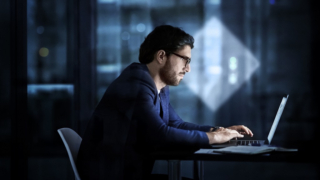 Mann sitzt vor Laptop